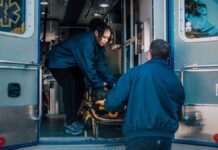 Overdose Deaths Fell for a Third Straight Year. Here Is What the Data Actually Says. Two paramedics loading a stretcher into an ambulance, illustrating emergency overdose response as US overdose deaths decline for a third year