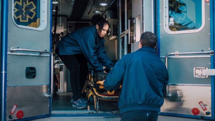 Two paramedics loading a stretcher into an ambulance, illustrating emergency overdose response as US overdose deaths decline for a third year