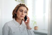 988 at Four Years: 23 Million Contacts and a Funding Model That Has Not Caught Up An adult talking on a smartphone beside a window in a bright room.