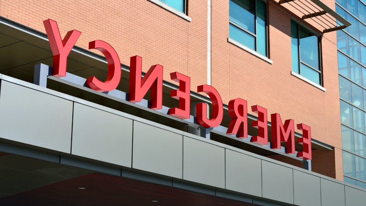 The illuminated entrance to a modern hospital emergency department.