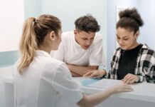 The Federal List of Buprenorphine Prescribers Is Gone. Here Is What Replaced It. A nurse assisting two people at a hospital reception desk, representing the front door to outpatient opioid use disorder treatment.