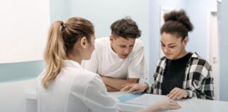 The Federal List of Buprenorphine Prescribers Is Gone. Here Is What Replaced It. A nurse assisting two people at a hospital reception desk, representing the front door to outpatient opioid use disorder treatment.