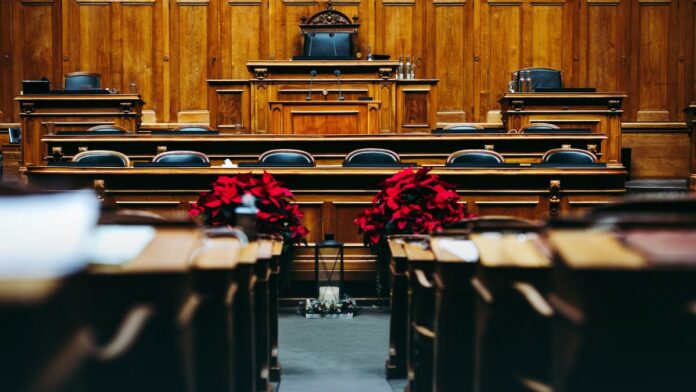 The interior of a wood-panelled courtroom with empty benches.