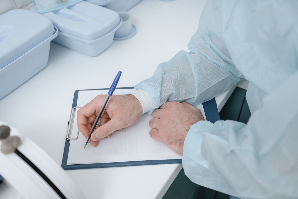 Gloved clinician recording newborn screening and toxicology results on a clipboard