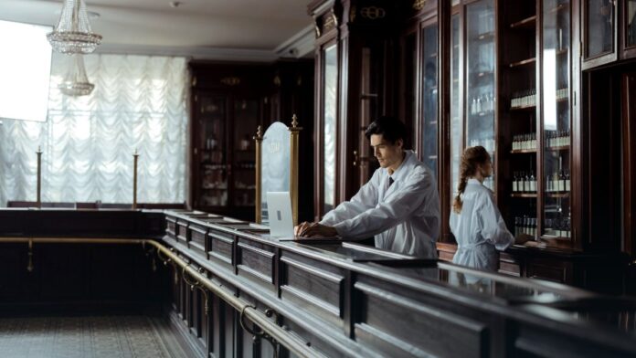 A pharmacist working behind a pharmacy counter, representing retail access to over the counter naloxone nasal spray. A pharmacist working behind a pharmacy counter, representing retail access to over the counter naloxone nasal spray.