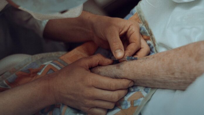 A healthcare worker giving an injection to an older adult patient in a clinical setting.