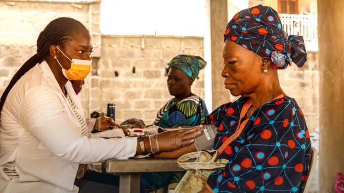 A healthcare worker checking a patient blood pressure at a community health site. A healthcare worker checking a patient blood pressure at a community health site.