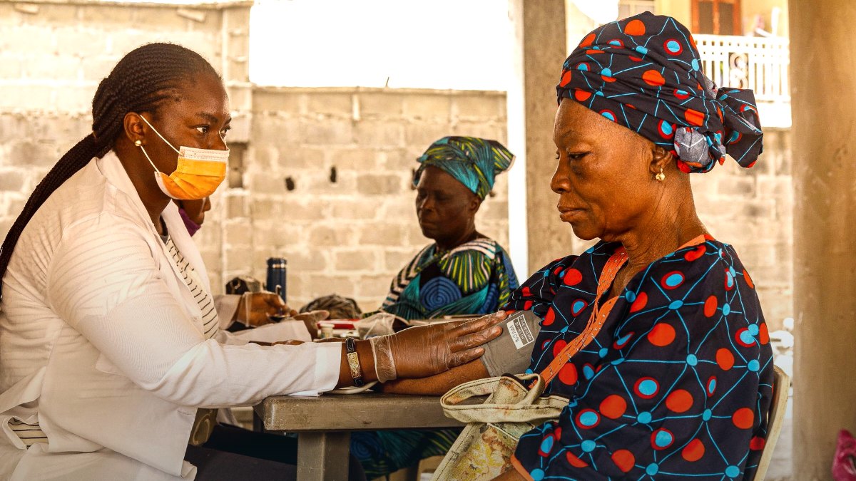 A healthcare worker checking a patient blood pressure at a community health site.
