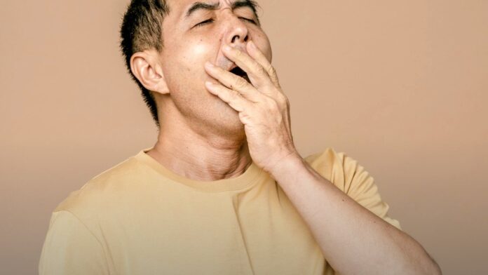 A person resting their head in one hand, appearing disoriented. A person resting their head in one hand, appearing disoriented.
