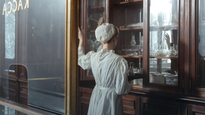 A pharmacy worker handling packaged medication behind a counter. A pharmacy worker handling packaged medication behind a counter.