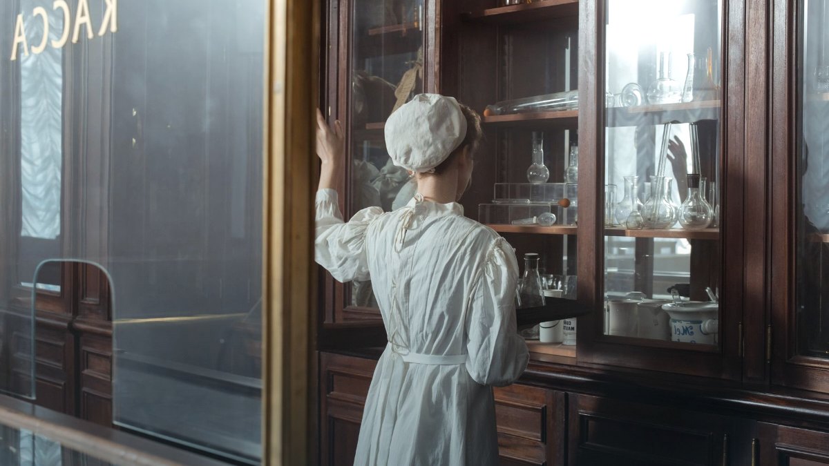 A pharmacy worker handling packaged medication behind a counter.
