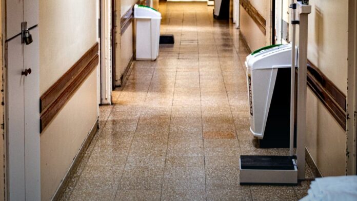 A quiet hospital corridor with daylight falling across the floor. A quiet hospital corridor with daylight falling across the floor.