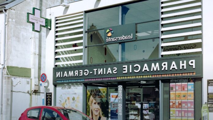A pharmacy interior with shelves of products behind a counter. A pharmacy interior with shelves of products behind a counter.